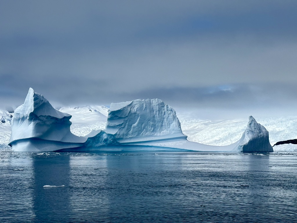 Three sculptural pillars of blue Antarctic ice above dark water